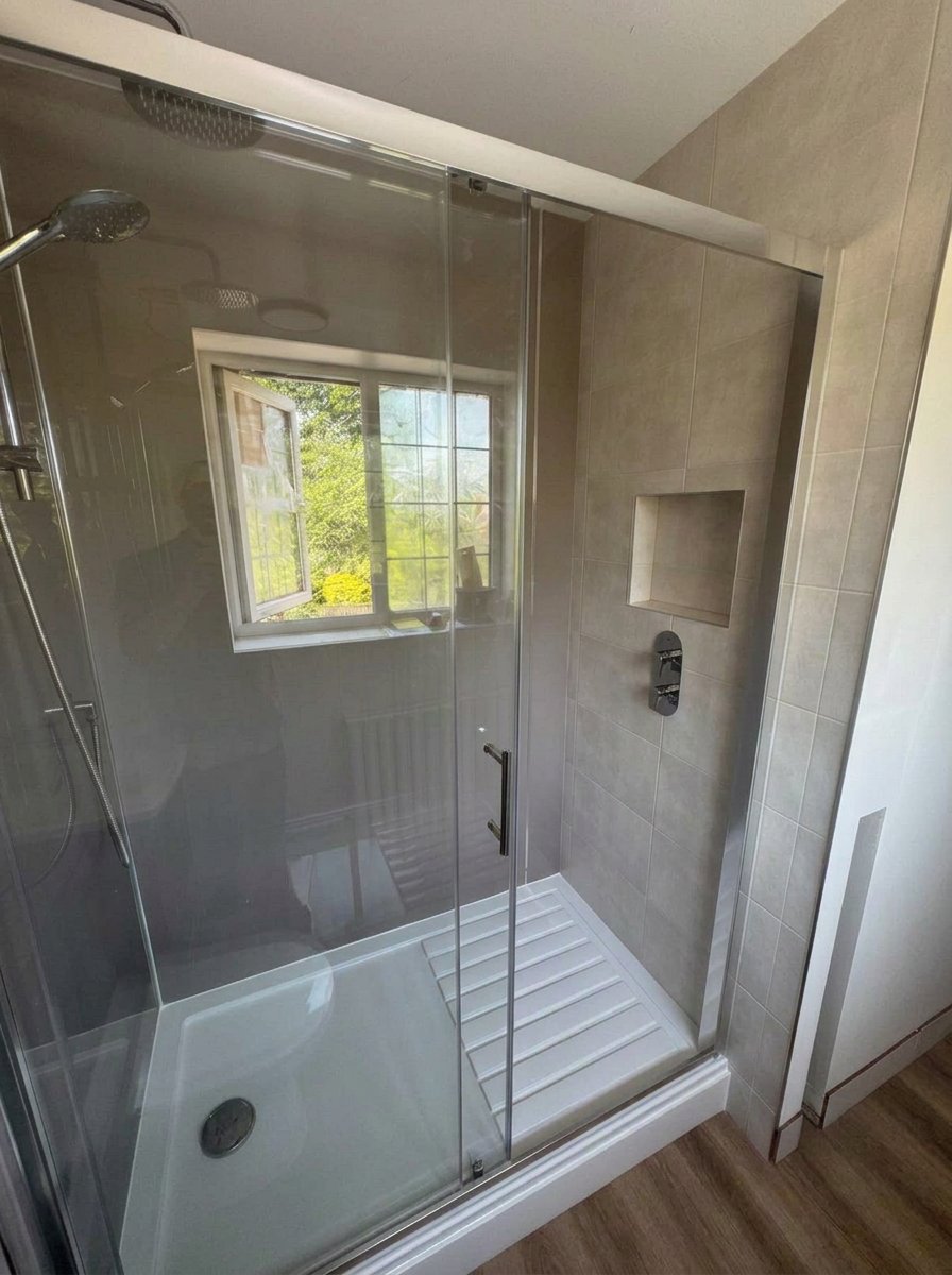 Finished sliding-door shower enclosure with tiled wall and recessed niche in a West Sussex shower room
