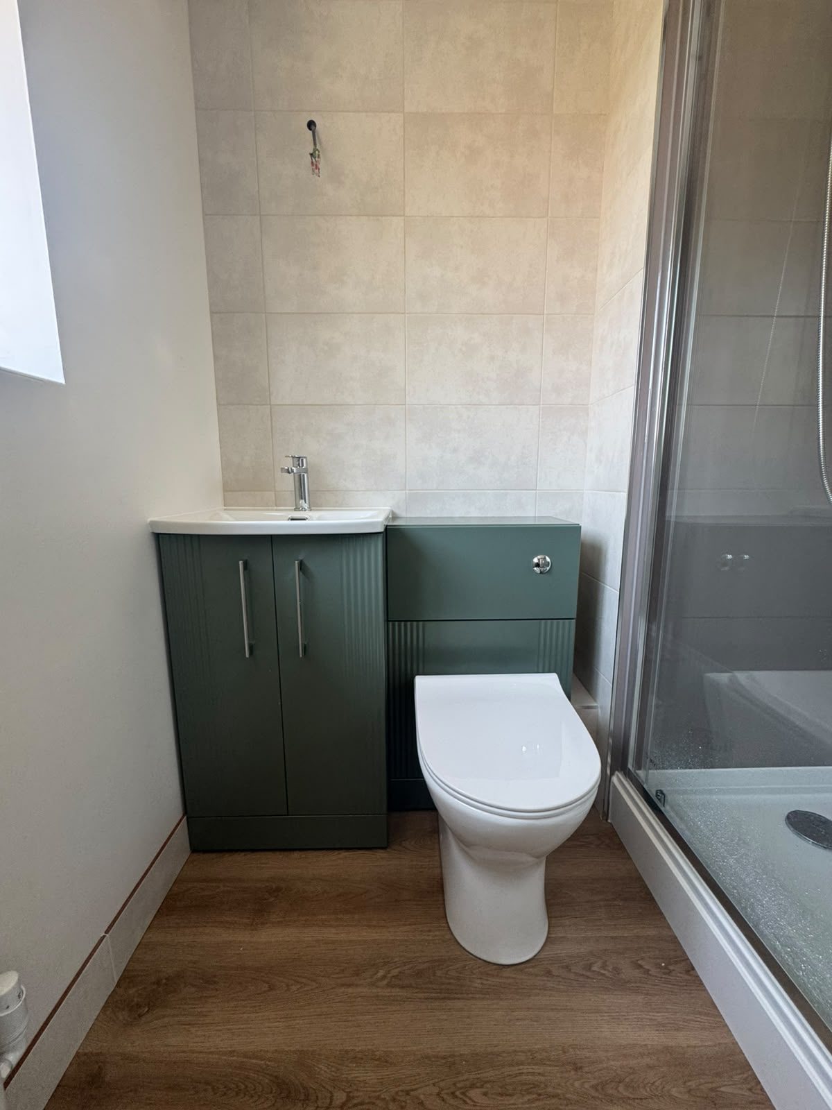 Green fluted vanity unit, back-to-wall toilet and chrome basin tap in a fitted shower room in West Sussex