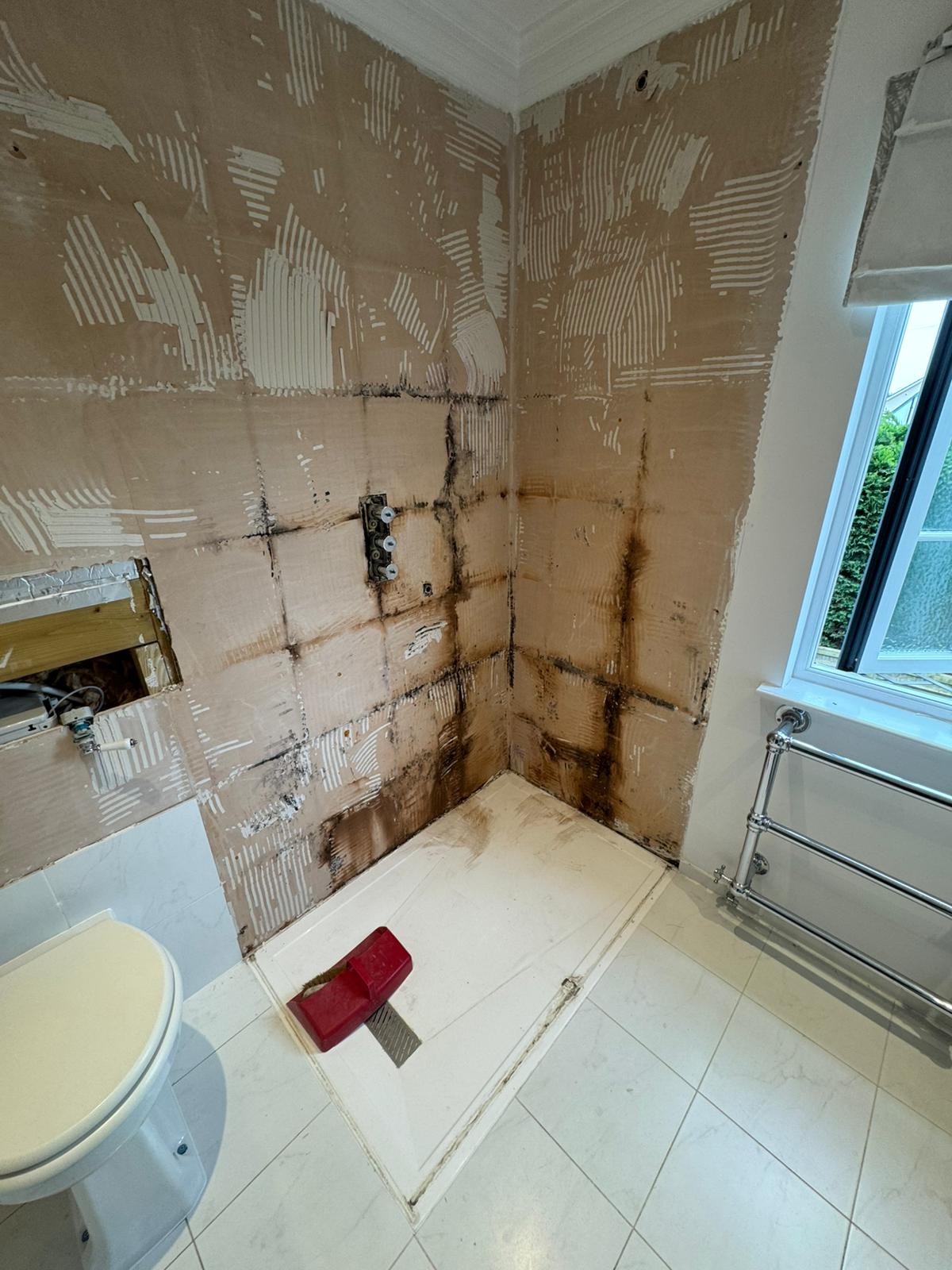 Bathroom walls stripped back showing black mould and water damage from a leak, before re-tiling by Adsett Bathrooms