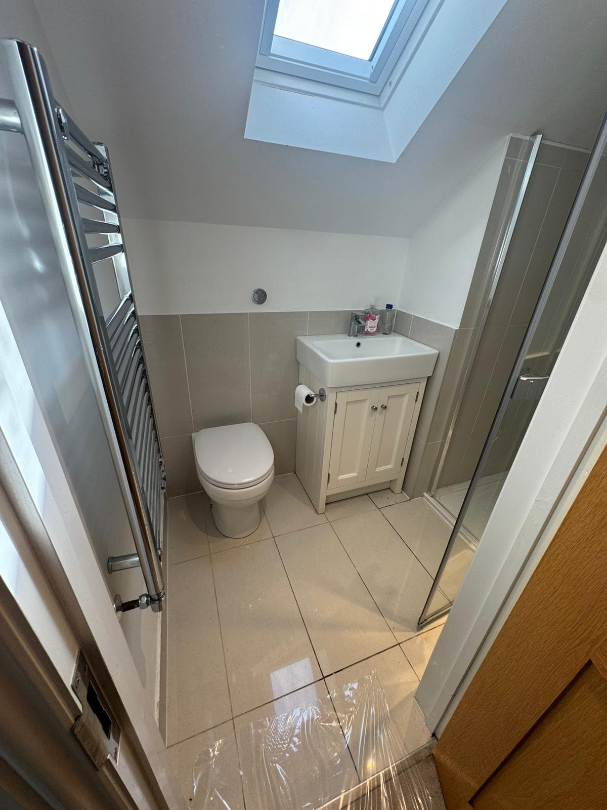 Finished loft shower room with re-tiled walls, refitted vanity, toilet and towel radiator by Adsett Bathrooms in West Sussex