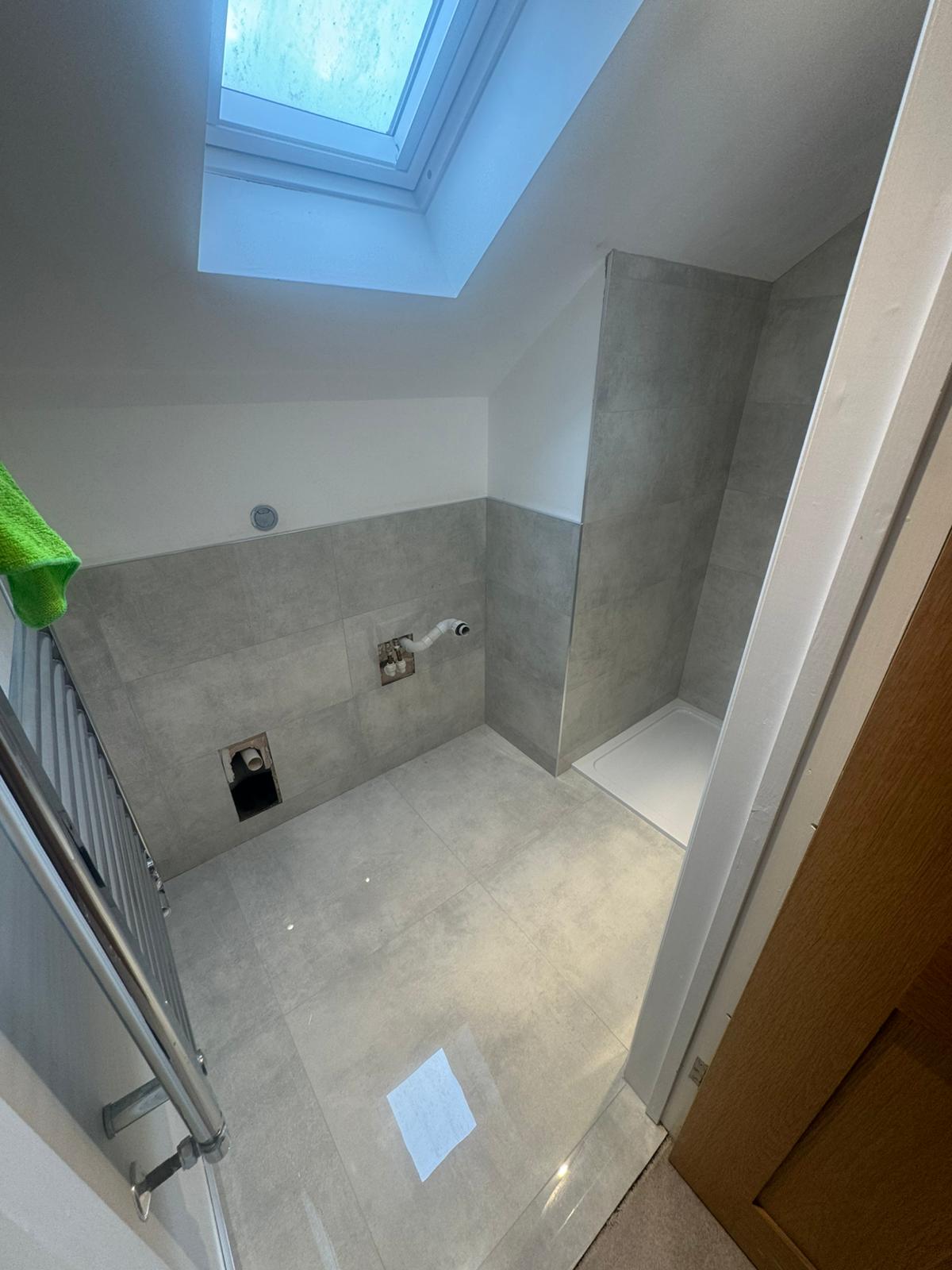 Loft shower room part-tiled with new shower tray, pipework and towel rail in West Sussex