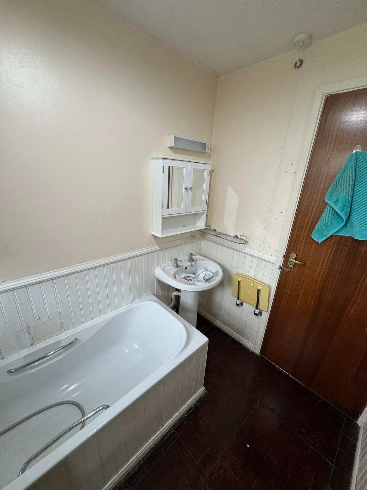 Dated bathroom with a bath and pedestal basin before an easy-access walk-in shower conversion by Adsett Bathrooms