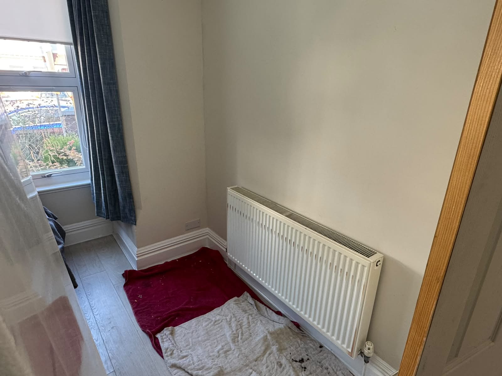 Old white panel radiator on its original wall, before being moved by Adsett Bathrooms in West Sussex