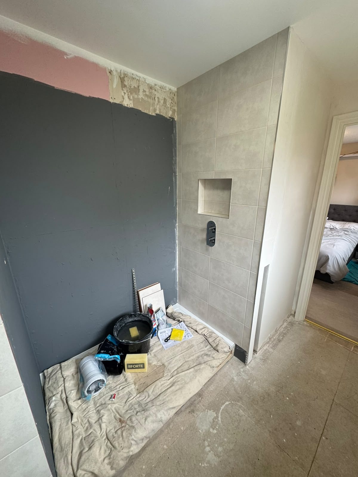 Tiled shower wall with recessed niche and shower valve part-way through a West Sussex shower room fit-out