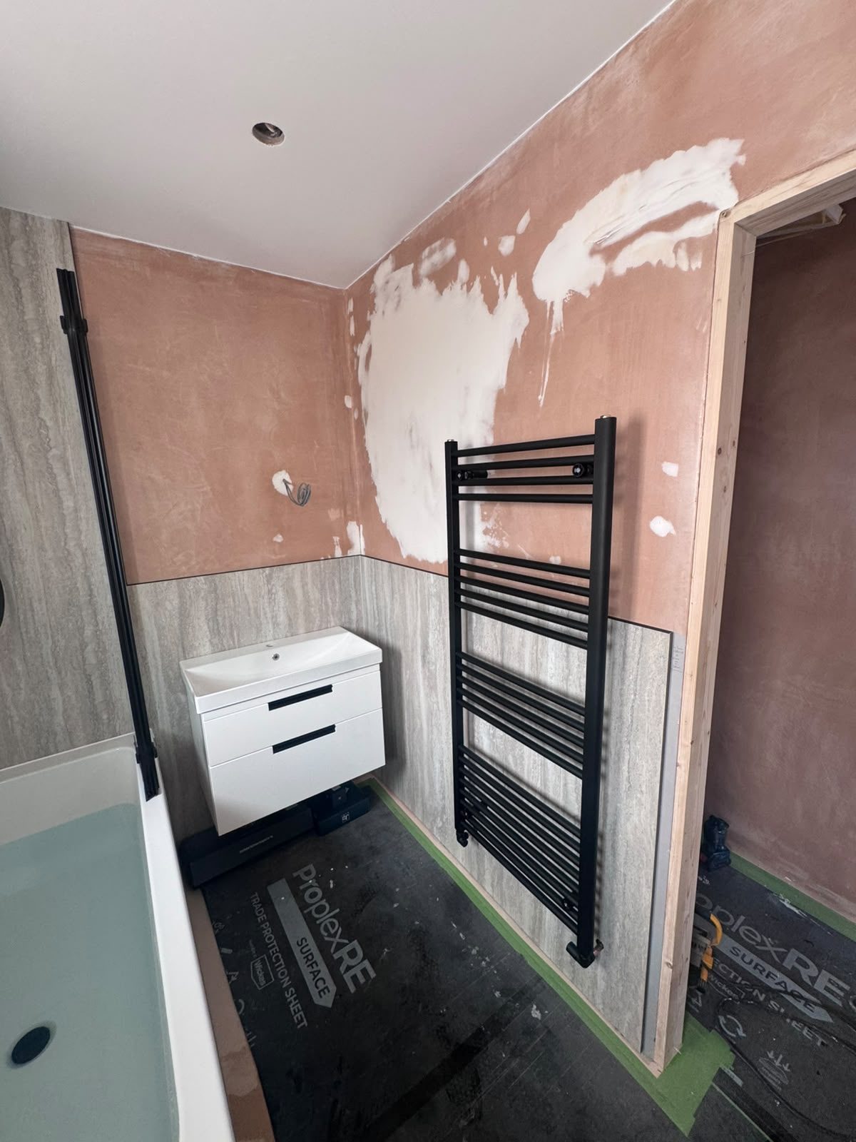 Wall-hung vanity unit and black heated towel rail in a matt black bathroom