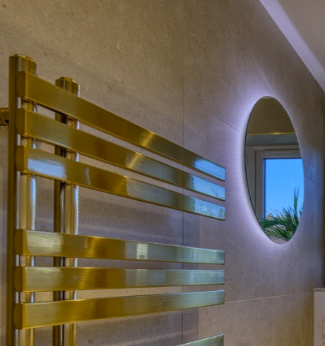 Brushed gold heated towel rail fitted on tiled wall